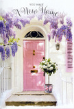 The scene shows a sunlit front door that feels very much like it could be found on a peaceful Sipson cul-de-sac, where neighbours pause to admire the flowers as they pass. The door itself is a soft, rosy pink, its gentle tone catching the afternoon light and creating a warm focal point against the crisp white walls. Overhead and to the side, wisteria trails in generous cascades, the blooms a dreamy mix of lavender and dusty purple that hang like delicate tassels. Their clustered petals create a textured canopy that almost brushes the top of the door, suggesting a sweet, drifting fragrance that blends with the scent of fresh air from nearby fields. At the foot of the doorway, positioned neatly on the step, stands a chic grey bucket filled to overflowing with white and cream roses. The roses are fully open, revealing layered petals that form soft, rounded cups, each one edged in faint ivory. Sprigs of green foliage thread between them, introducing natural variation and giving the arrangement a freshly gathered, garden-inspired character. Around the bucket, a soft pink ribbon is tied in a simple yet elegant bow, the colour nodding back to the painted door and bringing harmony to the composition. The sunlight falls lightly across the scene, creating gentle shadows that make the textures of wood, plaster, petals, and leaves stand out clearly. The overall mood is tender and hopeful, capturing the emotional hush of a new chapter-a floral housewarming gesture that might be delivered across Sipson to celebrate a move, offer congratulations, and quietly bless the threshold with warmth, comfort, and the promise of happy days ahead.